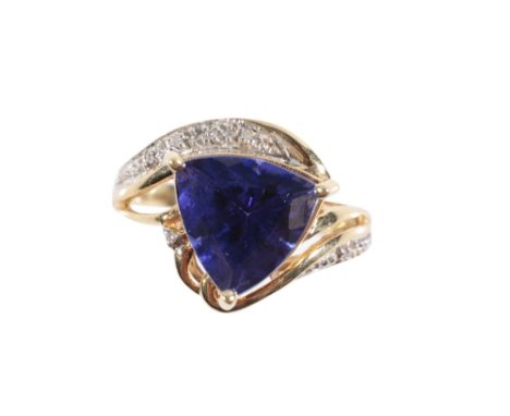 AN 18 CARAT GOLD TANZANITE DRESS RING, the triangular-cut tanzanite in a three claw setting, on a twisted shank set with eigh