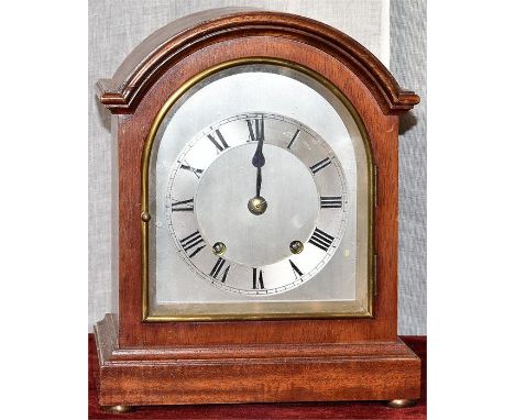 A mahogany inlaid bracket clock with silvered arched dial on squat bun feet. H=25, W=20.5, D=14cm
