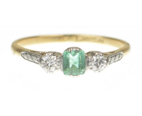 An emerald and diamond three stone ringThe central step cut emerald flanked by two round brilliant cut diamonds, the shank st