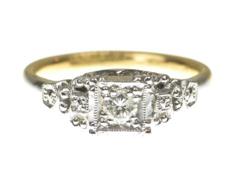 A diamond ringCentering a round brilliant cut diamond, within a square surround flanked by pierced shoulders, to a shank stam