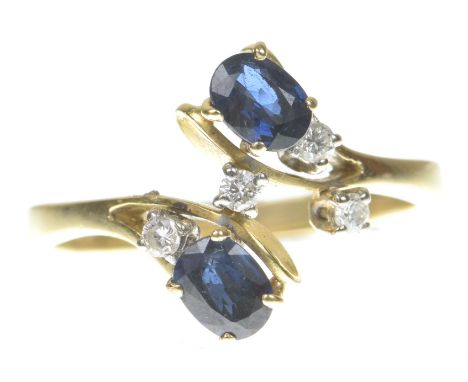 A sapphire and diamond crossover ringThe two oval shape sapphires to a cross over setting, with round brilliant cut diamond h