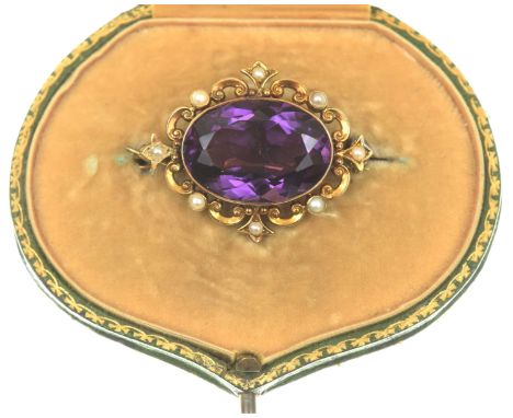 An amethyst and seed pearl broochThe oval shape amethyst to a seed pearl and pierced scroll surround, with a fitted brooch pi