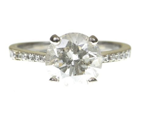 A diamond solitaire ringThe round brilliant cut diamond, claw set, to tapered round brilliant cut diamond shoulders, modelled