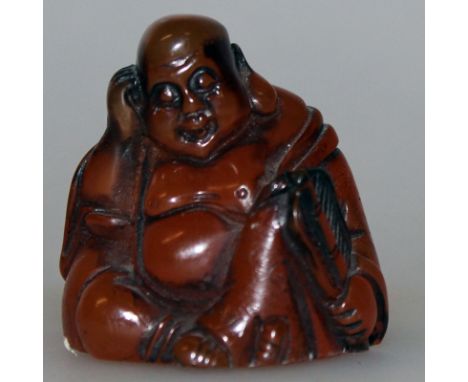 A SIGNED JAPANESE AMBER-LIKE NETSUKE OF HOTEI, the seated deity asleep and holding a fan, the base with an engraved signature