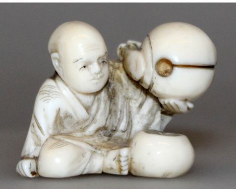 AN EARLY 20TH CENTURY SIGNED JAPANESE IVORY NETSUKE OF A SEATED BOY, bearing aloft a temple bell, the base with an engraved s