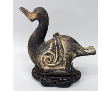 A CHINESE HAN STYLE CERAMIC MODEL OF A DUCK, together with a fitted carved hardwood stand, the whole with traces of pigmentat