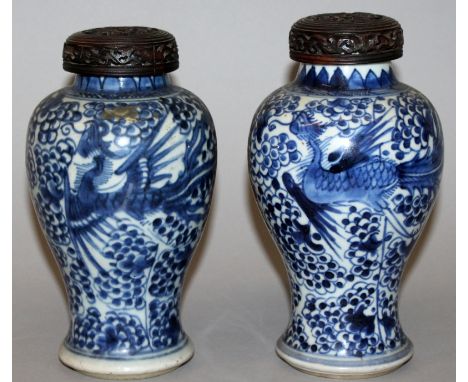 A PAIR OF CHINESE KANGXI PERIOD BLUE & WHITE PORCELAIN VASES, with a pair of pierced hardwood covers, each vase painted with 