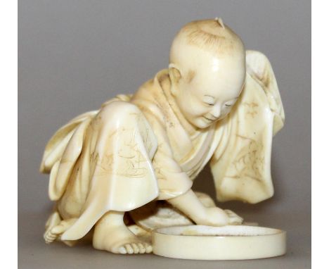 A SIGNED JAPANESE MEIJI PERIOD IVORY NETSUKE OF A SQUATTING BOY, looking at his reflection in a large hand mirror lying on th