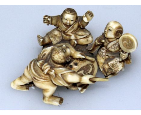 A GOOD QUALITY SIGNED JAPANESE MEIJI PERIOD STAINED IVORY NETSUKE OF A GROUP OF BOYS, playing over and around a drum bearing 