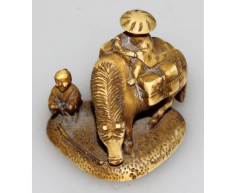 A SIGNED JAPANESE MEIJI PERIOD STAINED IVORY NETSUKE OF A TRAVELLER, seated on a horse and in the company of a boy attendant,