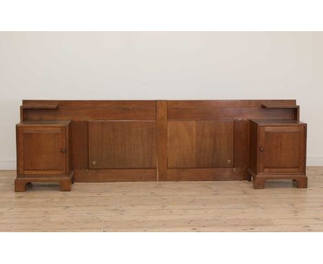 A Cotswold School oak headboard,with integral cupboards and shelves, in two parts, with chip-carved details, each cupboard en