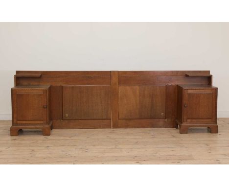 A Cotswold School oak headboard,with integral cupboards and shelves, in two parts, with chip-carved details, each cupboard en