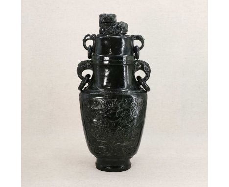 A Chinese spinach jade vase and cover,20th century, of compressed tapering form flanked by two mask and ring handles, carved 