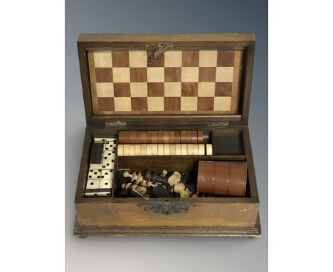An Edwardian mahogany games box containing chess pieces, draughts pieces, chess.