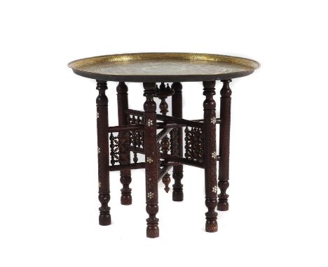 late 19th/early 20th century, with a repoussé brass charger top profusely decorated in Islamic script, raised on a collapsibl