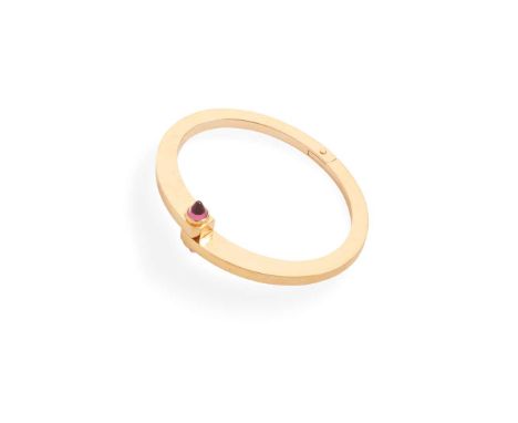 Cartier: A garnet 'Menotte' bangle  Of hinged design, the screw-down clasp set with two cabochon garnets, signed, stamped 75