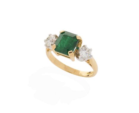  An 18ct yellow gold emerald and diamond three-stone ring  Claw-set with a square step-cut emerald and two small round brilli