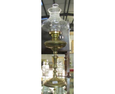 A brass oil lamp with cranberry font and complete with shade.