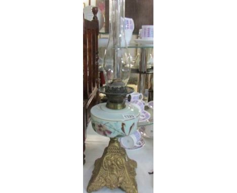 A Victorian oil lamp with floral painted green glass font.