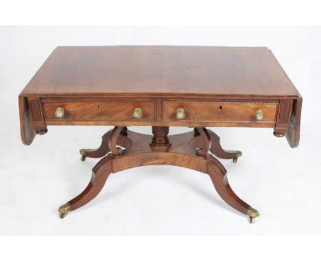 A GEORGE IV IRISH MAHOGANY TWO FLAP DROP LEAF SOFA TABLE with carved foliate decoration and fitted two drawers with brass han