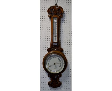 An Edwardian carved oak barometer/thermometer, retailed by Gamages, London, white scale and dial, floral carved case, c.1905