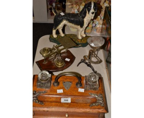 An Edwardian oak desk ink stand; a set of postal scales; another set of scale; a cast iron painted doorstop of a spaniel 