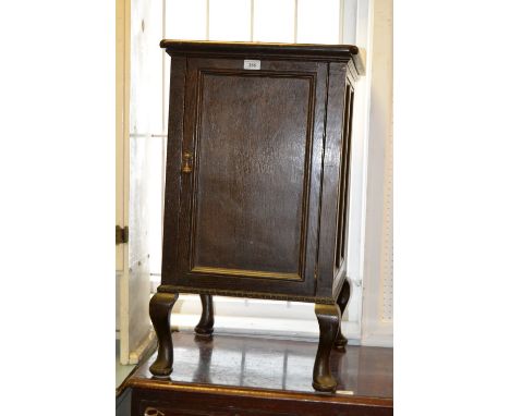 An early 20th century oak gramophone cabinet, converted into a storage cabinet, a single door enclosing storage with a single