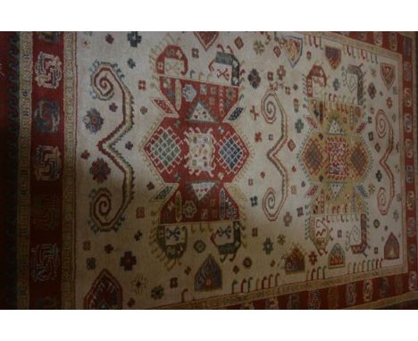 An Indian wool carpet, the central ivory field with geometric medallions flanked by geometric borders, 167cm x 225cm