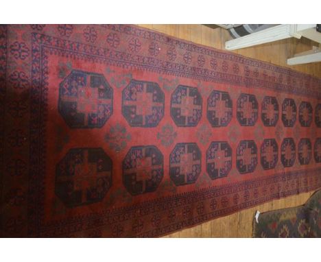 A finely knotted Afghan Bokhara hall rug, the central panel with twin rows of lattice and flowerhead borders, on red field, 3