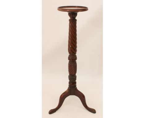 A mahogany torch&egrave;re - early 20th century, the dished circular top on a tapered spiral reeded and foliate carved column