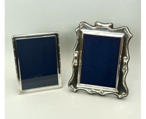 Two Elizabeth II silver photo frames - with easel backs, one of cartouche, scroll-edged form, by Carrs of Sheffield, 1990, 25