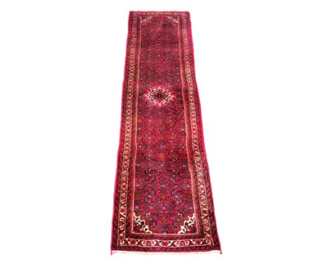 A Persian hand-knotted wool runner, probably Hamadan - second half 20th century, with a central red and ivory lozenge medalli