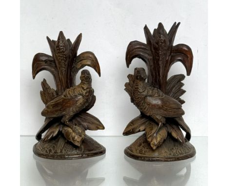 A pair of carved wooden Black Forest candlesticks - early 20th century, in the form of game birds perched on leaves beneath r