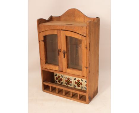 A pine part-glazed wall hanging cabinet - with an arched top with three quarter gallery, over a pair of glazed arched doors (