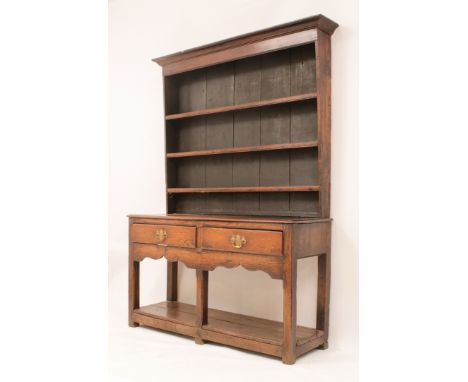 An early 18th century oak potboard dresser - the cavetto moulded cornice over a closed plate-rack with three shelves, the bas