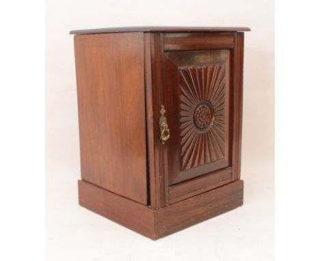 A small Edwardian mahogany bedside cupboard - the door with a rectangular fanned panel centred by a floral rondel, on a plint