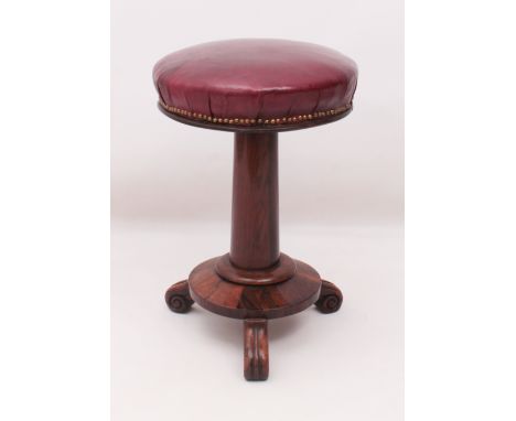 A William IV circular rosewood piano stool - the (later) dark red leather seat supported by a gun-barrel stem over a circular