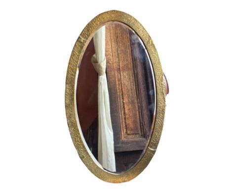 An Arts and Crafts hammered brass oval mirror. Circa 1900 -1910. Bevelled glass. Hangs portrait. 67cm x 45cm.  