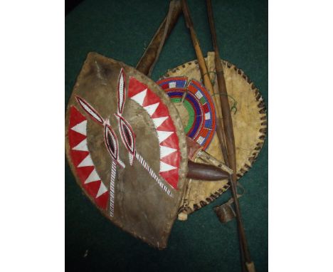 Selection of various African tribal items including hide sheilds, short spears, beadwork necklace, two sheath knives and a le