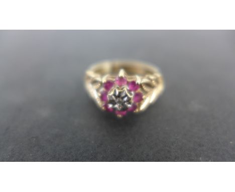 A 9ct gold diamond and ruby dress ring with a small central diamond surrounded by eight small rubies and stylized laurel leav