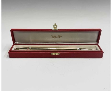 A Cartier gold plated pen, one end with a red enamel band the other blue, each end takes a screw-in Bic refill. 178mm. Red Ca