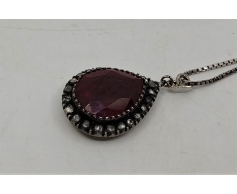 A white metal, ruby and diamond pendant, set large mixed pear shape cut ruby (length 20mm x width 15mm) bordered by numerous 