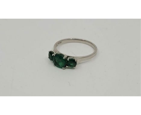 A 18ct. white gold three stone emerald ring, set three graduated round cut emeralds (centre stone approx. 7mm x 7mm x 4mm - e