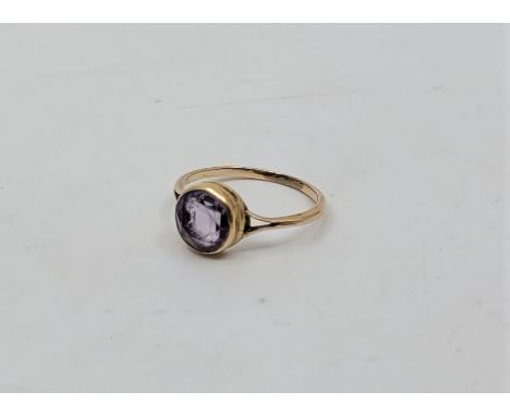 A precious yellow metal and amethyst ring, having central round mixed cut amethyst in rub-over setting, (yellow metal assesse