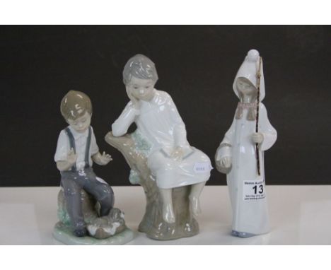 Two Lladro ceramic models of Children in nightclothes and a Nao model of a Boy with Puppy, tallest stands approx 22cm