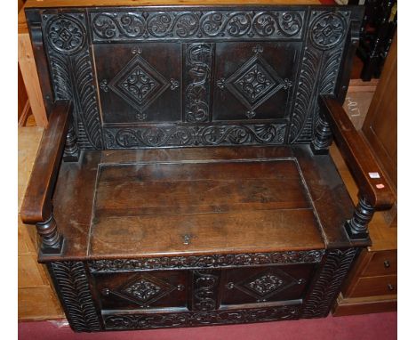 An antique joined and relief carved oak twin panelled fold-over monks bench, having typical hinged box seat base, width 121cm