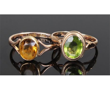 Two gold rings, the first with an orange oval stone, ring size O, the second with a green oval stone, ring size O, (2)