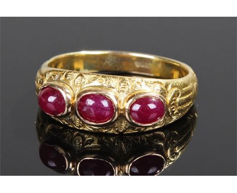 Yellow metal ruby set ring, with three cabochon rubies to the engraved shank, ring size O