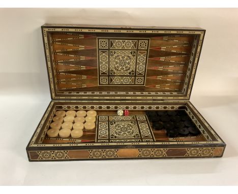 A Inlaid backgammon board, complete with set of 15 black and 15 white pieces. Outside of board has a grid of 64 squares. No r