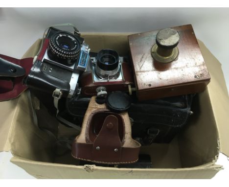 A box of cameras and accessories including a vintage box camera, Praktica etc.